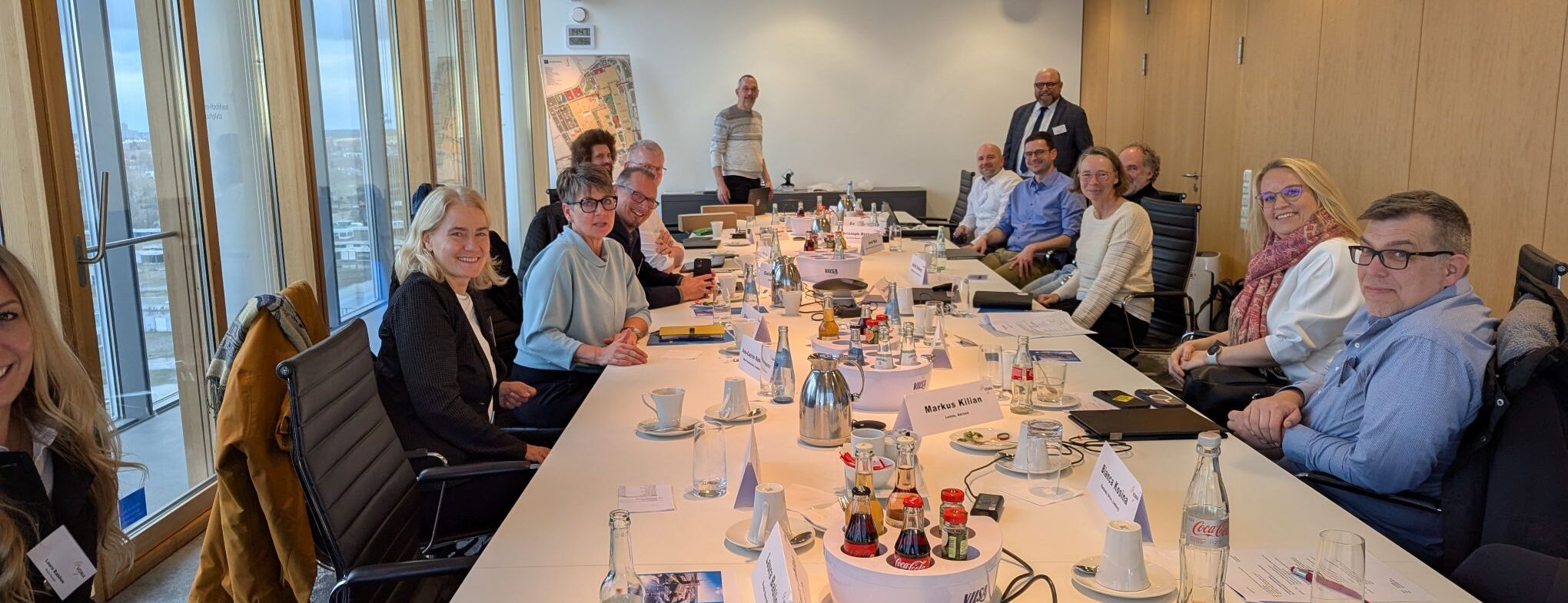 Kundenmeeting am großen Konferenztisch mit 14 Mitarbeitenden eines Marketingteams